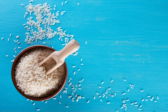 Clay brown plate with raw rice and wooden spatula - Stock Photo - Images