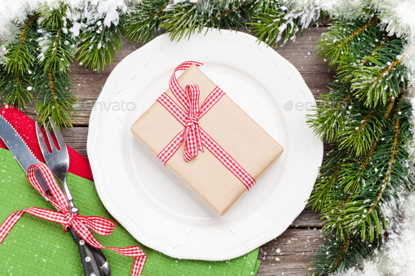 Christmas gift box over dinner plate, silverware, fir tree