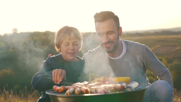 Father and Son Cook Sausages on Grill