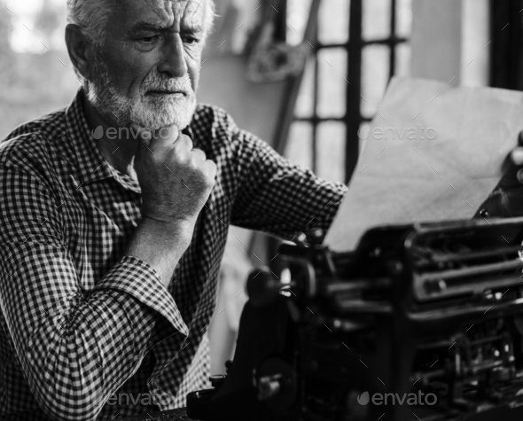 Senior caucasian man using vintage typewriter grayscale