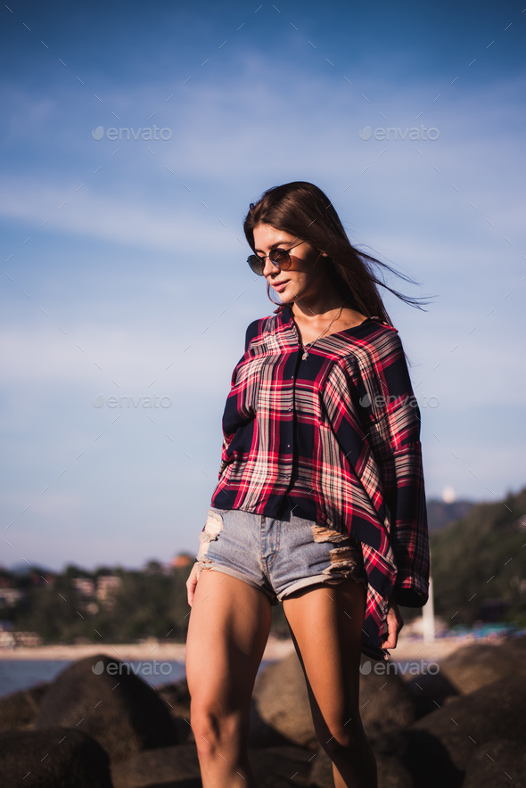 Mevrouw Verslaving bouwen Sexy Girl in flannel shirt on the rocky beach. Stock Photo by romankosolapov