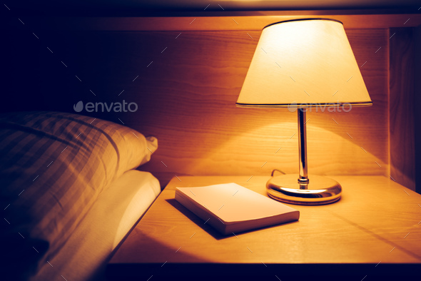 Book and lamp on night table in hotel room