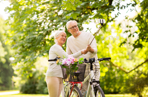 senior couple with bicycles taking selfie at park