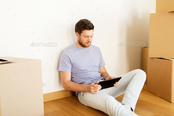 man with tablet pc and boxes moving to new home