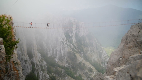 Two Young Guys Cross Abyss on Rope Bridge