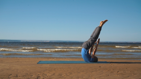 Young Man Doing Thoracic Stretching on a Rock at Sunset Light alt