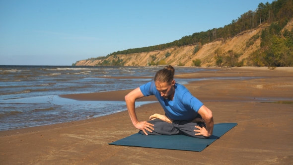 Young Man Doing Thoracic Stretching on a Rock at Sunset Light alt