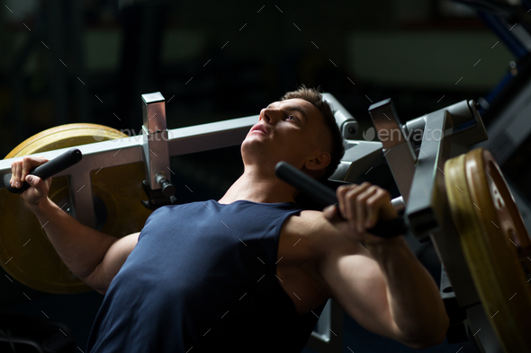 man doing chest press on exercise machine in gym