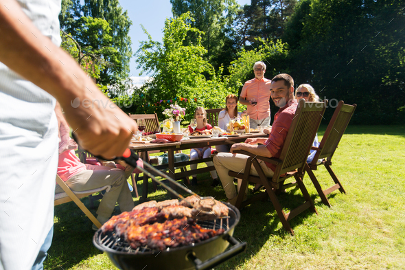man cooking meat on barbecue grill at summer party
