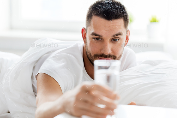 man in bed with glass of water at home