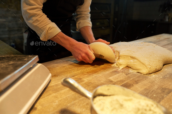 baker portioning dough with bench cutter at bakery