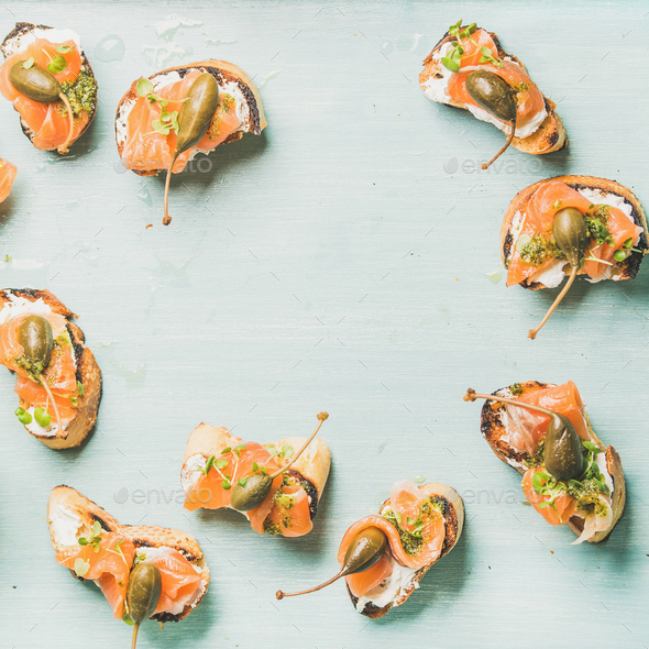 Crostini with smocked salmon, pesto sauce , watercress, capers. Blue background - Stock Photo - Images