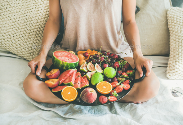 Young girl holding tray full of fresh seasonal fruits - Stock Photo - Images