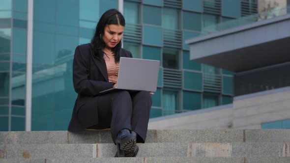 Happy Young Hispanic Businesswoman Spending Free Time Outdoors Typing on Laptop Social Network alt