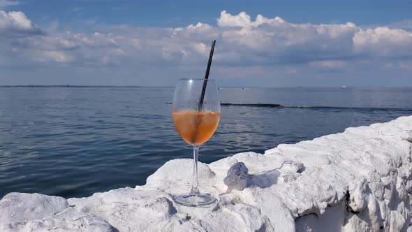 Pan View Cocktail Wine Glass on White Stone Fencing at Seaside with Sea Waves Background