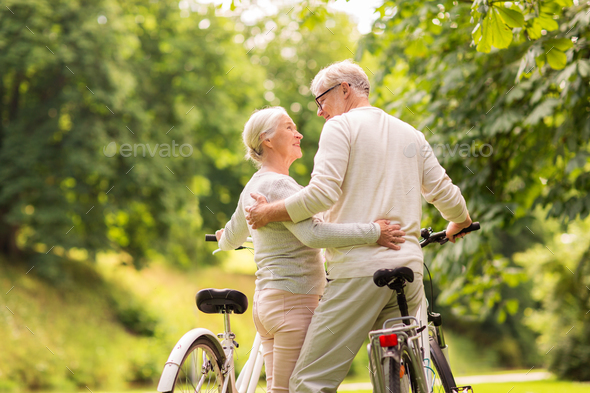 happy senior couple with bicycles at summer park