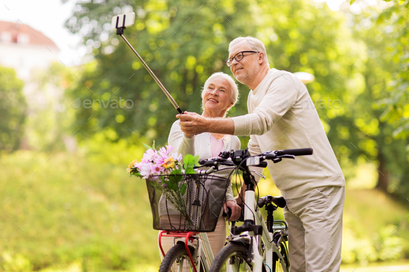 senior couple with bicycles taking selfie at park