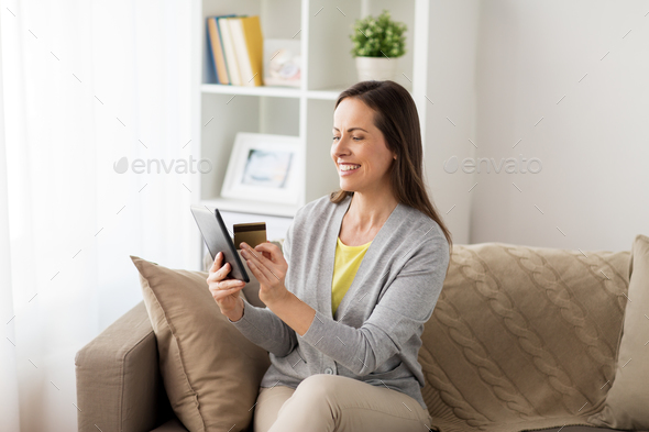 happy woman with tablet pc and bank card at home