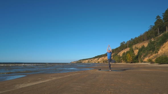 Strong Man Practicing Difficult Yoga Pose on the Beach alt