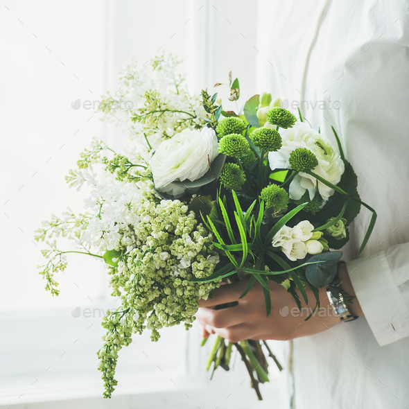 Young woman wearing white clothes holding flowers bouquet. Wedding concept - Stock Photo - Images