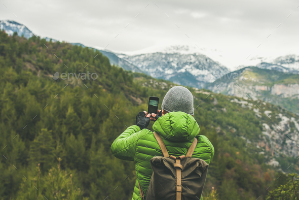 Young man traveller making photo of mountains and green slopes - Stock Photo - Images