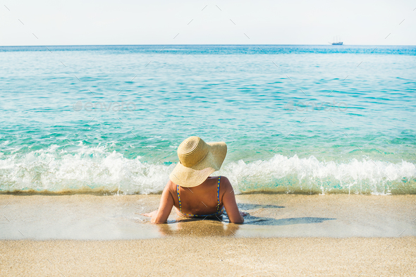 Woman lying on sand and enjoying clear blue sea waters - Stock Photo - Images