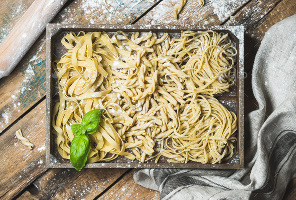 Homemade uncooked Italian pasta in wooden tray over shabby background - Stock Photo - Images