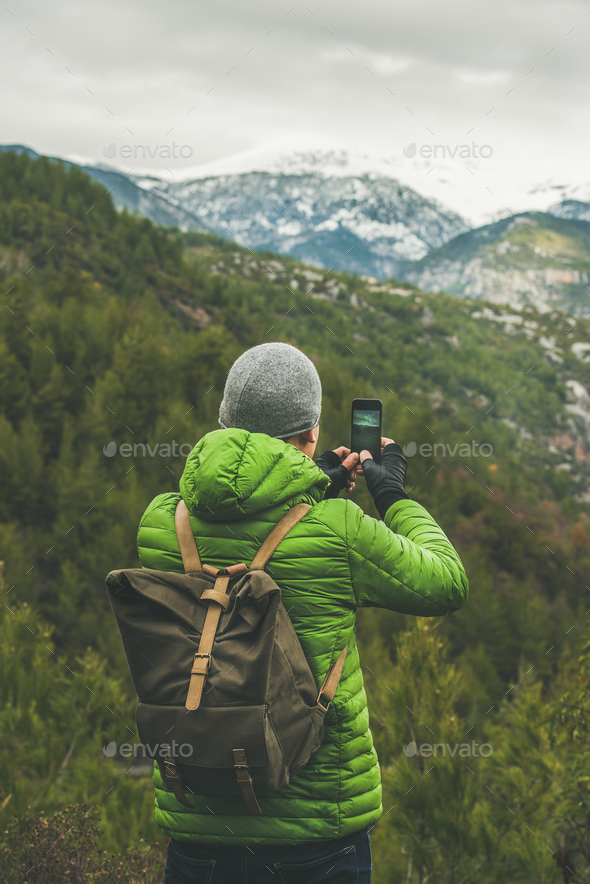 Young man traveller making photo of green valley and slopes - Stock Photo - Images