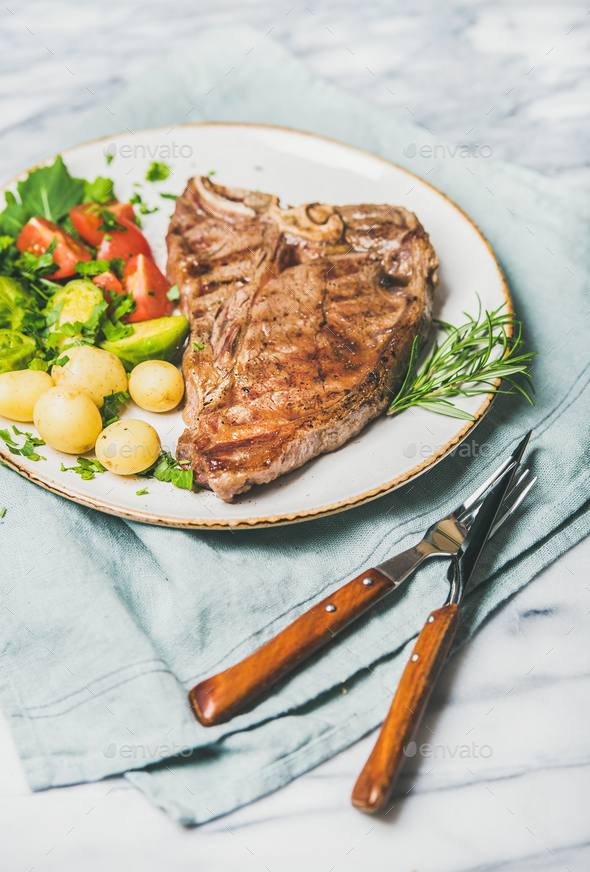 Cooked beef tbone steak with vegetables and rosemary in plate - Stock Photo - Images