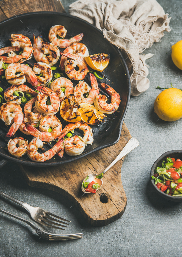 Seafood dinner with grilled tiger prawns in pan, grey background