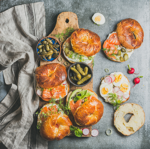 Variety of bagels with different fillings on rustic wooden board - Stock Photo - Images