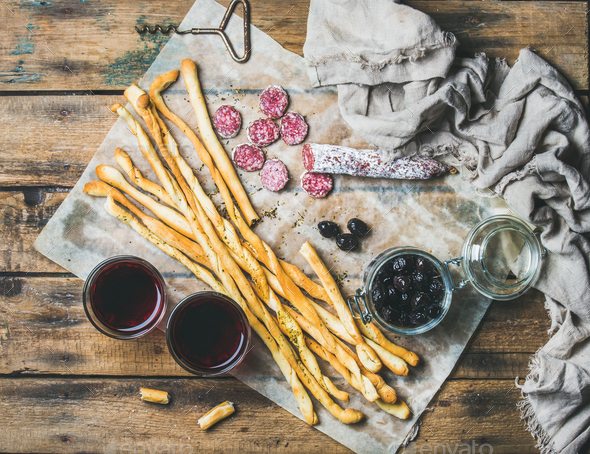 Grissini bread sticks, sausage, olives and red wine, wooden background - Stock Photo - Images