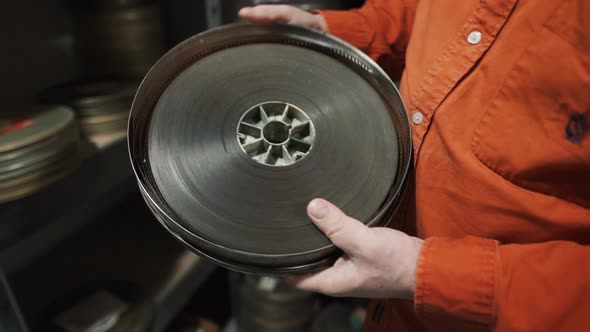 A man opens an old metal round box with an old film strip inside alt