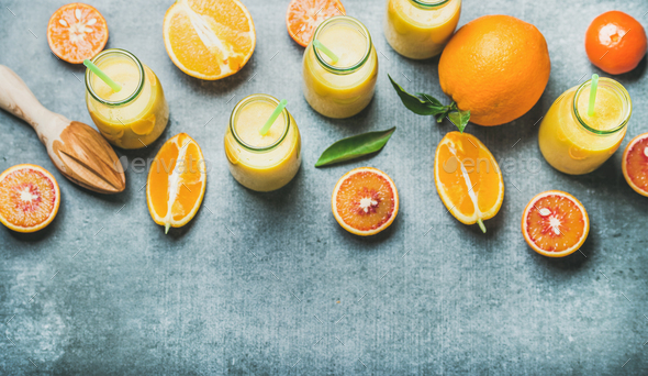 Healthy yellow smoothie in bottles over grey concrete background - Stock Photo - Images