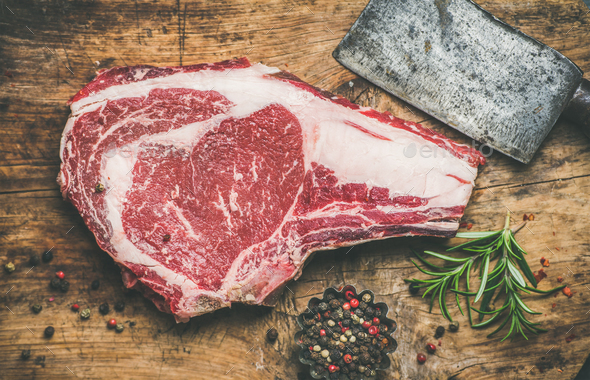 Raw beef steak rib-eye with seasoning and knife, rustic background - Stock Photo - Images