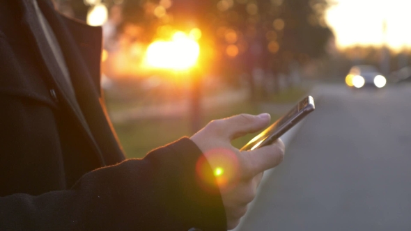 Well-dressed Trendy Man Talking with Mobile Phone in a City on Sunset Time