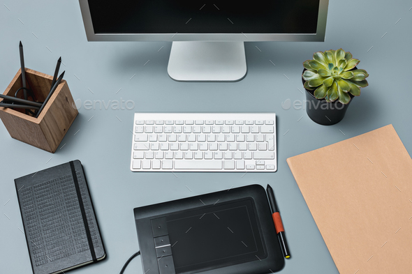 The gray desk with laptop, notepad with blank sheet, pot of flower, stylus and tablet for retouching - Stock Photo - Images