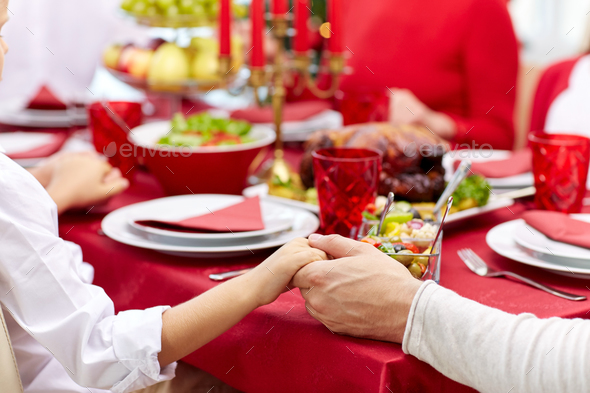 family having holiday dinner and praying at home