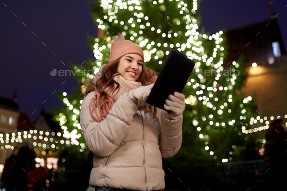 woman with tablet pc at christmas tree outdoors