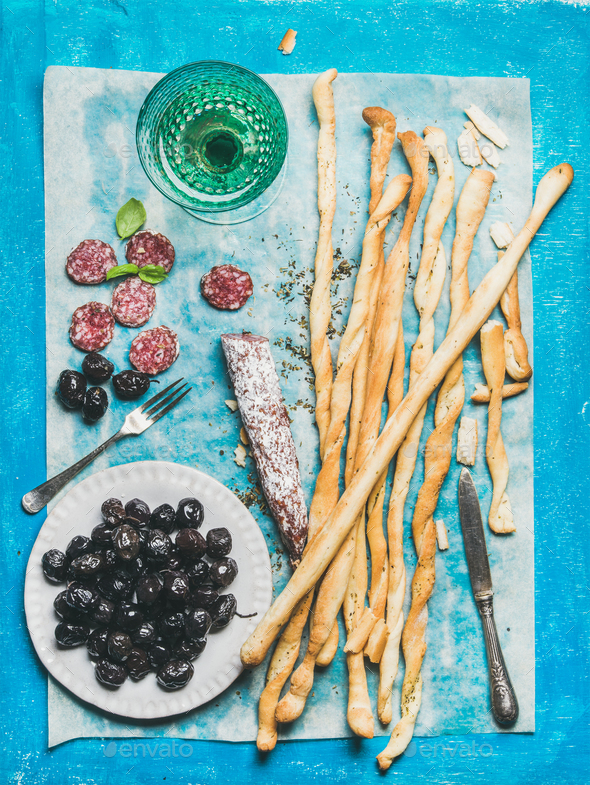 Grissini bread sticks, sausage, olives and white wine, blue background - Stock Photo - Images