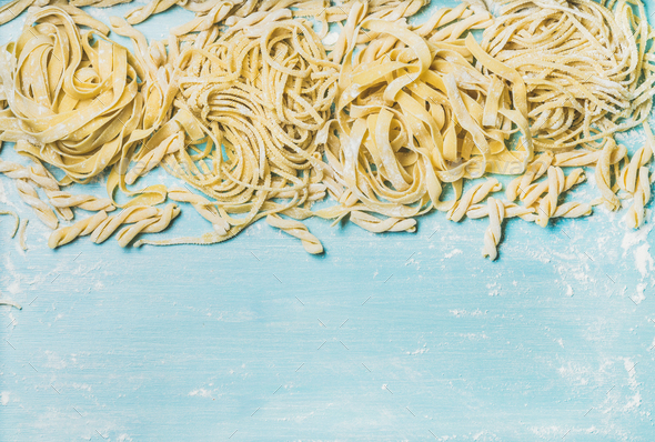 Various homemade uncooked Italian pasta with flour on blue background - Stock Photo - Images