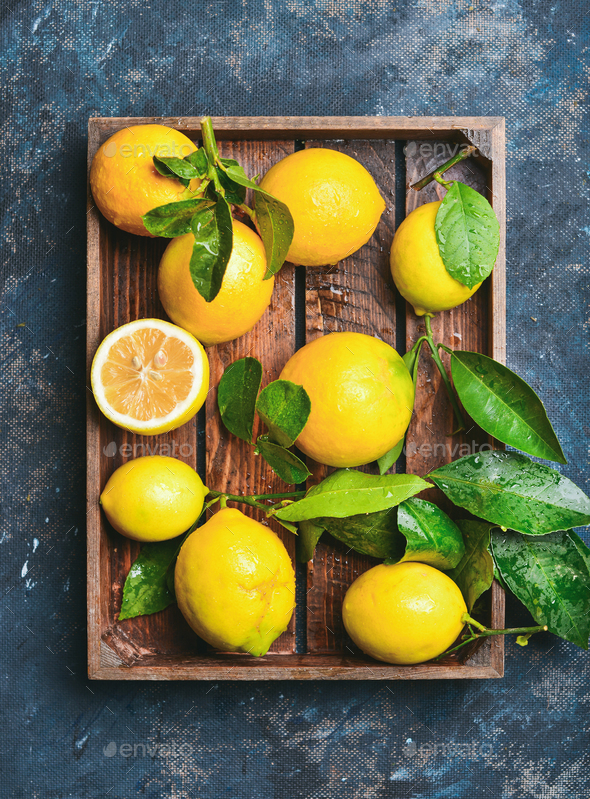 Freshly picked lemons with leaves in rustic wooden tray - Stock Photo - Images