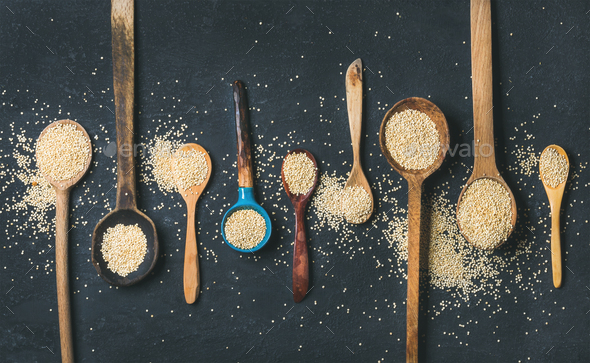 Quinoa seeds in different spoons over black stone background - Stock Photo - Images