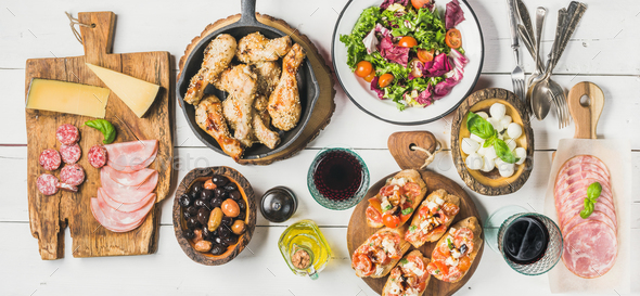 Rustic table set with chicken, salad, different snacks and wine - Stock Photo - Images