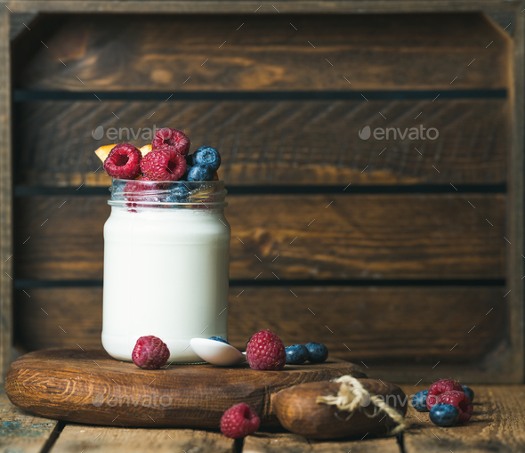 Glass jar of yogurt with fresh garden berries and peach - Stock Photo - Images