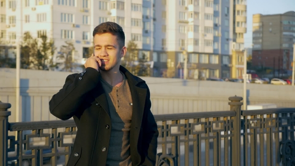 Well-dressed Trendy Man Talking with Mobile Phone in a City on Sunset Time