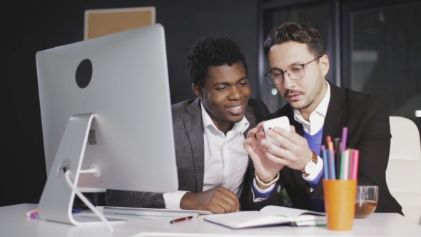 Boss Shows His Employee a Pictures on the Smartphone in the Office