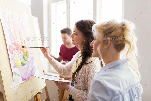 woman artist with easel painting at art studio Stock Photo by dolgachov