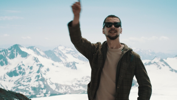 Young Bearded Man Pointing at Peaks at Snowy Mountains with Scenic View