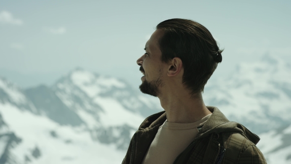Young Bearded Man at Mountain Top with Scenic View Squint Eyes and Talking